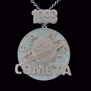 May include: A diamond-encrusted pendant necklace with a silver chain. The pendant features the number "1993" at the top, with a circular design below. The circular design includes a planet with rings and the word "COMETA".