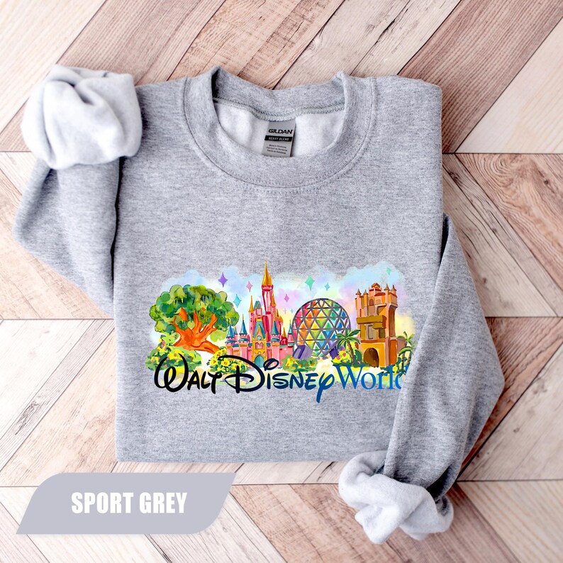 May include: Sport grey sweatshirt featuring a colorful graphic of Walt Disney World landmarks. The design includes a castle, a geodesic sphere, and other park icons. The text "Walt Disney World" is printed below the graphic in black and blue.