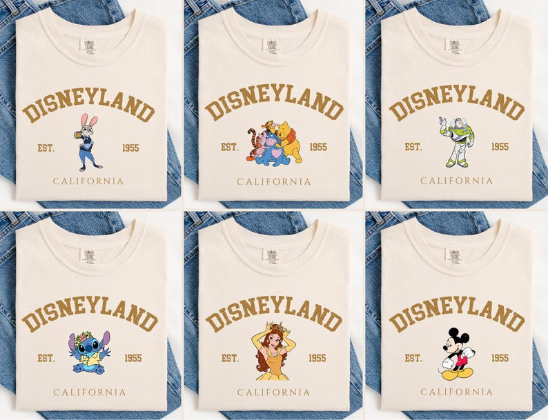 Pu&ograve; includere: T-shirt color crema con la scritta "DISNEYLAND" in oro ad arco. Ogni maglietta presenta una grafica diversa di un personaggio Disney, tra cui Judy Hopps, Winnie the Pooh, Buzz Lightyear, Stitch, Belle e Topolino. Il testo "EST. 1955 CALIFORNIA" &egrave; anch'esso stampato.