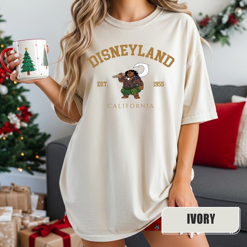 Pu&ograve; includere: T-shirt color avorio con grafica Disneyland. Il design presenta la scritta "Disneyland" sopra un'illustrazione di un personaggio dei cartoni animati che tiene un'arma, con "EST. 1955 CALIFORNIA" sotto. La maglietta ha una vestibilit&agrave; ampia.
