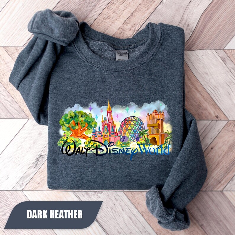 May include: Dark heather gray sweatshirt featuring a colorful watercolor design of Walt Disney World landmarks. The design includes the Tree of Life, Cinderella Castle, Spaceship Earth, and Tower of Terror. The text "Walt Disney World" is also included.