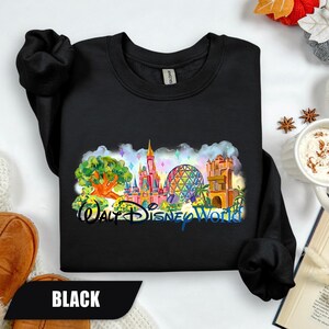 May include: Black sweatshirt featuring a colorful graphic of Walt Disney World landmarks, including a castle, Spaceship Earth, and the Tree of Life. The words "Walt Disney World" are written below the graphic in a stylized font.
