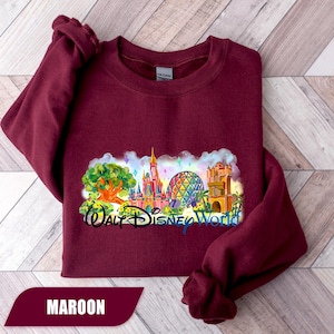 May include: Maroon sweatshirt featuring a colorful graphic of Walt Disney World landmarks, including a castle, Spaceship Earth, and a tree. The words "Walt Disney World" are written in a stylized font below the graphic. The word "MAROON" is displayed at the bottom.