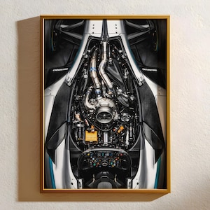 Puede incluir: Impresión enmarcada que muestra los intrincados detalles de un motor de coche de carreras de Fórmula 1. La imagen destaca la compleja red de tuberías, cables y componentes mecánicos en plata, negro y azul. El volante y el salpicadero son visibles.