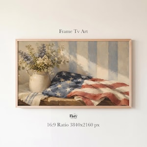 Può includere: Una stampa d'arte digitale rettangolare intitolata Frame Tv Art che mostra una brocca in ceramica bianca riempita con fiori selvatici blu e bianchi accanto a una bandiera americana piegata su una superficie di legno contro una parete a righe.