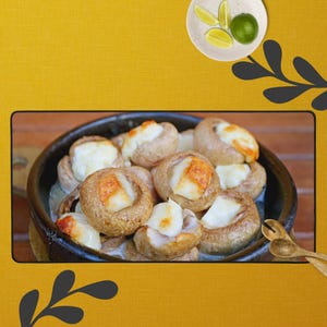 Puede incluir: Un cuenco oscuro lleno de champiñones horneados rellenos de un relleno cremoso blanco y cubiertos con una corteza dorada. Un plato pequeño con rodajas de lima y una lima entera en el fondo. Utensilios de madera para servir.
