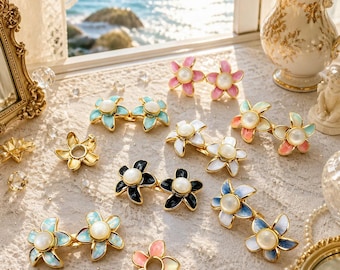 May include: A collection of flower-shaped hair clips featuring enamel petals in various colors including pink, blue, black, and white, each centered with a round white faux pearl. The clips are arranged in pairs and singles, showcasing a glossy finish.