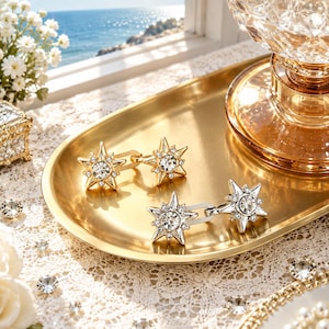 May include: Two pairs of star-shaped cufflinks crafted from polished gold-tone and silver-tone metal. Each cufflink features a central round clear crystal surrounded by smaller accent stones arranged in a radiating starburst pattern.