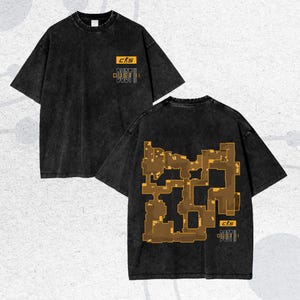 Puede incluir: Dos camisetas negras con un aspecto vintage descolorido. Una camiseta muestra el texto "CKS DUST II" en amarillo y blanco. La otra camiseta presenta un diseño de mapa en marrón y amarillo, con el mismo texto. Ambas camisetas tienen mangas cortas.