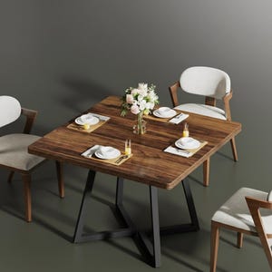 May include: A square wooden dining table with a dark finish, set for four. The table has a black metal base and is surrounded by four chairs with light-colored upholstery and wooden frames. A vase of flowers sits in the center.