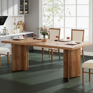 Könnte beinhalten: Ein großer, rechteckiger Esstisch aus Holz mit natürlicher Oberfläche. Der Tisch hat dicke, massive Beine und ist mit Tellern, Besteck und Weingläsern gedeckt. Zwei Stühle mit beiger Polsterung sind sichtbar, zusammen mit einer Blumenvase.