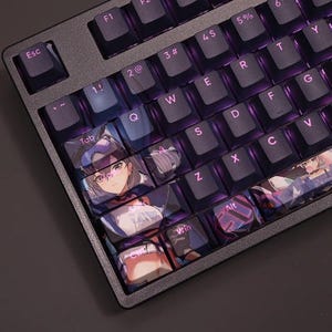 Könnte beinhalten: Eine schwarze mechanische Tastatur mit violetter Hintergrundbeleuchtung. Die Tastenkappen zeigen Anime-Kunst. Die Tastatur hat Standardtasten, einschließlich Esc, Tab, Shift und Alt. Die Tastenkappen sind schwarz mit lila Schrift und Kunstwerken.