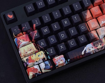May include: Black mechanical keyboard with custom keycaps featuring anime-style illustrations. The keycaps display colorful artwork of anime characters. The keyboard has a standard QWERTY layout with black keys and white lettering.
