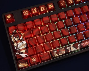 May include: A black mechanical keyboard with red keycaps. The keycaps feature various anime-style illustrations and symbols. The keyboard has a Fairy Tail theme, with the logo and character art visible on the keys.