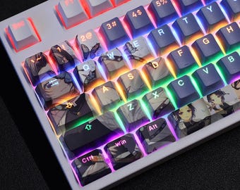 Op de afbeelding: Een wit mechanisch toetsenbord met aangepaste keycaps met anime-personageontwerpen. De keycaps hebben kleurrijke achtergrondverlichting, met gezichten van personages en vlindermotieven. Het toetsenbord heeft een standaard QWERTY-indeling.
