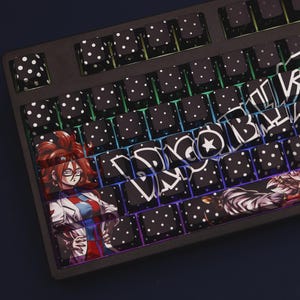 May include: Black mechanical keyboard with custom keycaps. Most keycaps are black with white polka dots. Some keycaps feature anime character art and stylized text. The keyboard has a black frame and a rainbow gradient backlight.