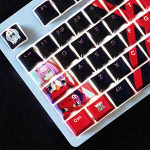 May include: A custom keyboard with black and red keys, and anime-themed keycaps. The keyboard has a light blue base. Some keys are red with white text, and others feature anime character designs. The Ctrl key is red.