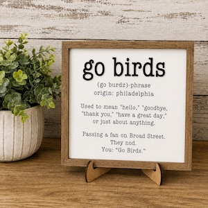 Może przedstawiać: Kwadratowy drewniany znak z białym tłem i czarnym tekstem: go birds (go burdz)-phrase origin: philadelphia. Used to mean "hello," "goodbye," "thank you," "have a great day," or just about anything. Passing a fan on Broad Street. They nod. You: "Go Birds."