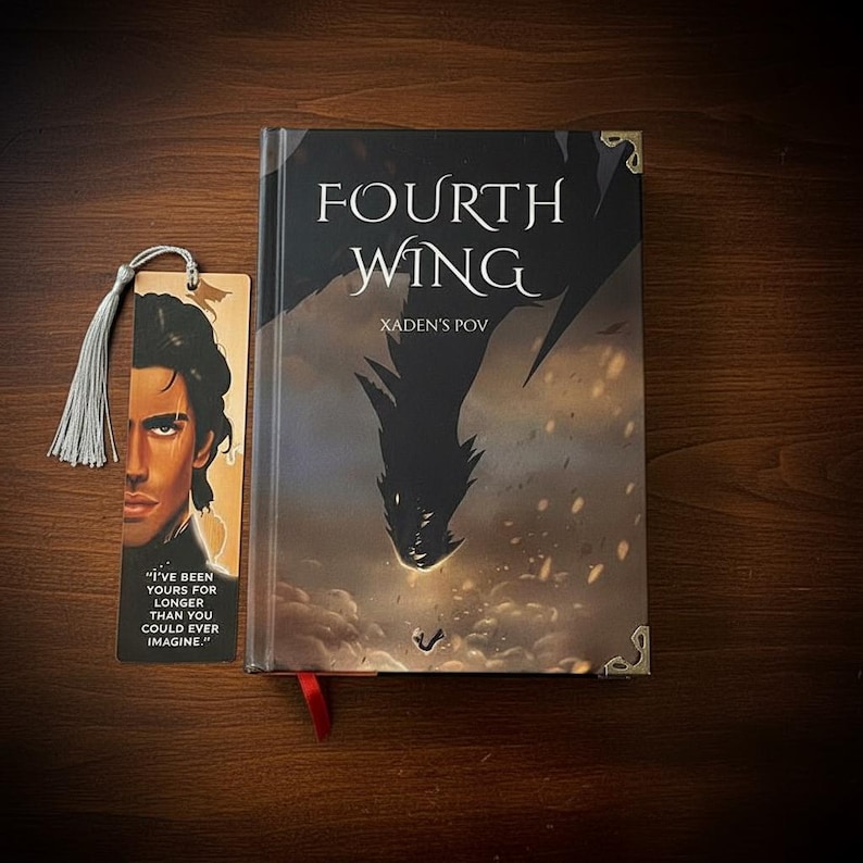 May include: A hardcover book titled "FOURTH WING" with "XADEN'S POV" text. A bookmark with a portrait and quote, "I'VE BEEN YOURS FOR LONGER THAN YOU COULD EVER IMAGINE." is next to the book. The book has a dragon illustration.