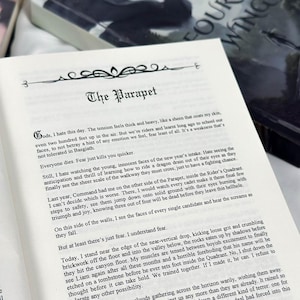 May include: Open book with text on a white page. The title "The Parapet" is at the top, with text below. The book is open to a page with multiple paragraphs of text. The book is on a light-colored surface.