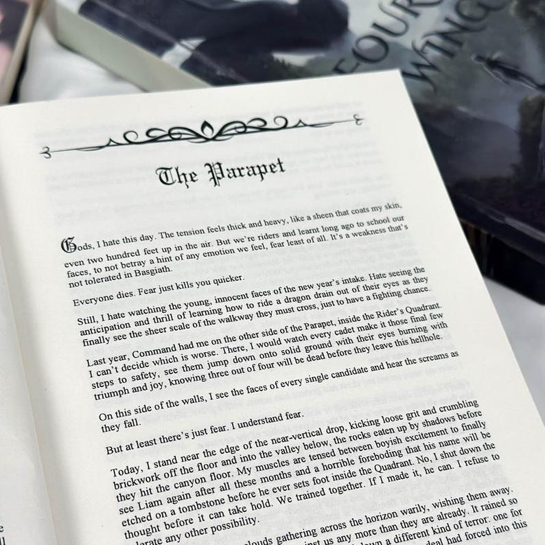 May include: Open book with text on a white page. The title "The Parapet" is at the top, with text below. The book is open to a page with multiple paragraphs of text. The book is on a light-colored surface.