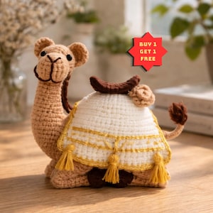 May include: A crocheted camel toy in shades of tan, brown, and cream. The camel has a saddle with gold trim and tassels. The text "BUY 1 GET 1 FREE" is on a red star-shaped sign.