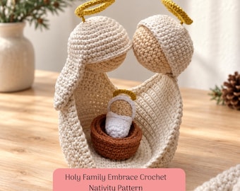 Puede incluir: Un conjunto de natividad de ganchillo con dos figuras de hilo color crema con halos amarillos, abrazando a una pequeña figura envuelta en blanco dentro de una cesta de hilo marrón. El texto "Holy Family Embrace Crochet Nativity Pattern" aparece en rosa.