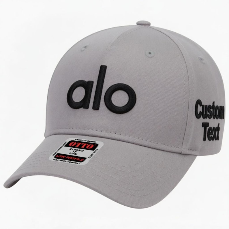 Pu&ograve; includere: Un cappellino da baseball grigio chiaro con la scritta "alo" in lettere nere sul davanti. Il lato destro del cappellino riporta le parole "Custom Text" in nero. Una piccola etichetta "OTTO" &egrave; sulla visiera.