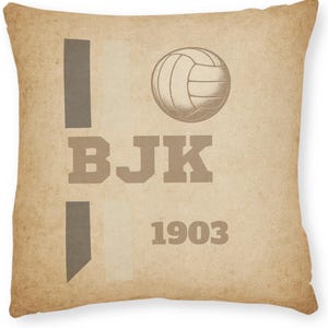 May include: Square pillow with a vintage design. The pillow features the letters "BJK" in a bold font, a volleyball graphic, and the year "1903". The background has a distressed, aged paper appearance, with vertical gray stripes.