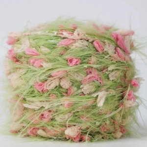 Op de afbeelding: Een bolletje getextureerd garen in tinten lichtgroen, roze en crème. Het garen heeft een pluizig, fuzzy uiterlijk met kleine, bloemachtige clusters van roze en crème. Geschikt voor knutselprojecten.