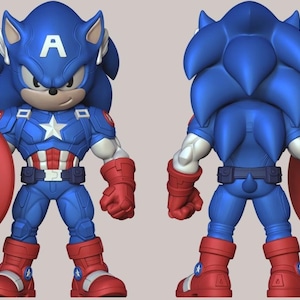 Op de afbeelding: Een blauw beeldje van Sonic the Hedgehog verkleed als Captain America, met een schild. De figuur staat in een heldenpose, met een rood, wit en blauw kleurenschema. De voor- en achterkant van de figuur zijn afgebeeld.