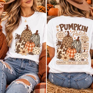 May include: A white t-shirt featuring a graphic of various pumpkins with different patterns including leopard print, cow print, plaid, and polka dots. The back design includes the text Pumpkin Patch, Fresh From The Patch, Farm Fresh, Locally Grown, Autumn Picked, Pumpkins, Corn Maze, and Apple Cider.