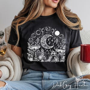 Könnte beinhalten: Dunkelgraues Heather-T-Shirt mit weißer Grafik eines Halbmonds, Pilzen, Kristallen und Himmelselementen. Der Text "Dark Grey Heather" steht unten. Ein lässiges Kleidungsstück.