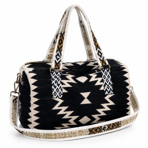 May include: A black and cream-coloured duffel bag with a geometric pattern. The bag has two handles and a detachable shoulder strap. The handles and strap feature a decorative design with gold and black accents. The bag is approximately 25 cm tall and 46 cm wide.