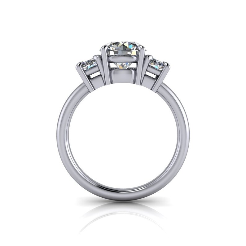 Pu&ograve; includere: Un anello di fidanzamento in argento a tre pietre con una grande pietra centrale rotonda e due pietre pi&ugrave; piccole a forma di pera su entrambi i lati.