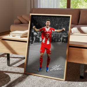 May include: A framed vertical poster featuring a color photograph of a soccer player in a red and white jersey with the letter T and number 6, celebrating with arms raised. The background is black and white, and a white signature is at the bottom.