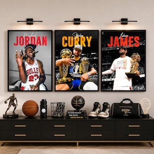 May include: Three framed wall posters featuring basketball players Michael Jordan, Stephen Curry, and LeBron James, each holding trophies. Below, a black console table displays a basketball figurine, a ball, a water bottle, books, trainers, and a duffel bag.