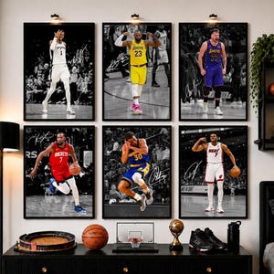 May include: A set of six framed basketball posters featuring professional players in action, including LeBron James and Kevin Durant, with printed signatures. Each poster displays a player in a team uniform on a court, with a black and white background.