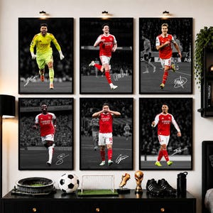 May include: Six framed posters featuring Arsenal football players in red and white kits on a black and white background. Each poster displays a player in action, including a goalkeeper in yellow, with a white signature printed on the bottom corner.