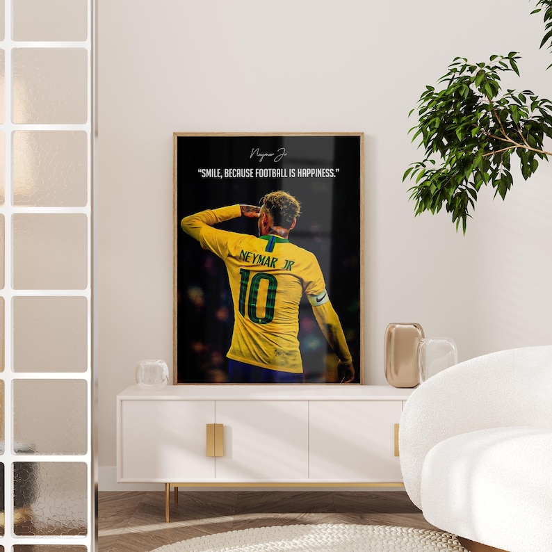 K&ouml;nnte beinhalten: Ein gerahmtes vertikales Poster, das einen Fu&szlig;ballspieler in einem gelben Trikot mit der Nummer 10 und dem Namen NEYMAR JR auf dem R&uuml;cken zeigt. Der Text &uuml;ber dem Spieler lautet: "SMILE, BECAUSE FOOTBALL IS HAPPINESS." Der Hintergrund ist dunkel und unscharf.