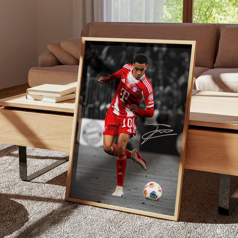 May include: A framed vertical poster featuring a color photograph of a soccer player in a red and white jersey with the number 10, dribbling a soccer ball on a field, set against a black and white background with a white signature overlay.