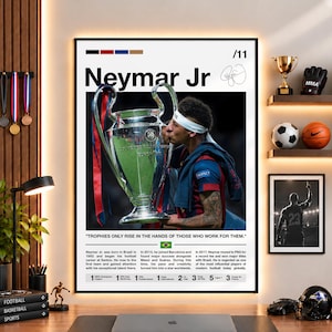 Op de afbeelding: Een verticale poster met Neymar Jr. die de UEFA Champions League trofee kust. Het ontwerp bevat zijn naam, een handtekening, een citaat en een biografische samenvatting met carrièrestatistieken. De poster hangt aan een muur met sfeerverlichting.