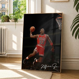 Könnte beinhalten: Gerahmter Druck mit Michael Jordan im Chicago Bulls-Trikot, in der Luft, kurz davor, einen Basketball zu dunken. Das Bild ist vor einem schwarzen Hintergrund mit einem Basketballkorb. Der Druck enthält Jordans Unterschrift.