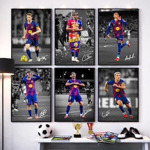 May include: Six framed prints featuring soccer players in action, wearing blue and red uniforms. Each print has a black and white background, with the players in color. The prints are displayed above a white table with soccer-themed accessories.