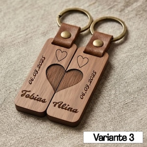 May include: Two wooden keychains with a heart design. Each keychain has a leather strap and a metal ring. One keychain is engraved with the name "Tobias" and the date "06.03.2025", the other with "Alina" and the same date. The text "Variante 3" is at the bottom.