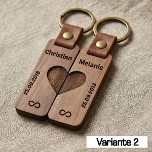 May include: Two wooden keychains with leather straps and metal rings. Each keychain is engraved with a name, date, and infinity symbol. The keychains, when placed together, form a heart shape.