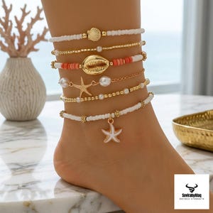 Pode incluir: Um conjunto de seis tornozeleiras em camadas com missangas brancas, contas metálicas douradas, pequenas pérolas artificiais, contas cilíndricas cor de coral, um berloque de concha búzios dourada, uma estrela-do-mar e um pendente de estrela-do-mar em esmalte branco.