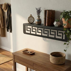 May include: A decorative wall shelf with a black frame and a Greek key design. The shelf holds a small clock, vases, books, and potted plants. A wooden console table with a woven basket and a decorative tray is below the shelf.