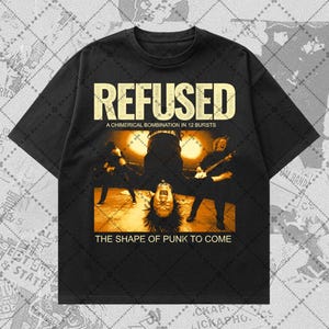 May include: A black short-sleeve t-shirt featuring a graphic print of a band performing on stage. The text reads REFUSED, A CHIMERICAL BOMBINATION IN 12 BURSTS, and THE SHAPE OF PUNK TO COME. The image shows a musician upside down in the center.