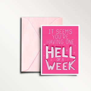 May include: Pink greeting card with the text "It seems you're having one hell of a week" in white lettering with a pink background and white stars.